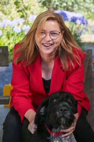 Michelle Scott Tucker wearing a red jacket holding a black dog.